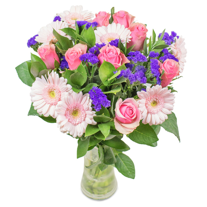A striking bouquet arranged by a Wealdstone florist features a sophisticated display of approximately eight pink roses-some tightly budded, others gently opening-creating an alluring spiral at the heart of the composition. Flanked by clusters of pale pink gerbera daisies, their large, symmetrical faces and creamy centres add brightness and softness akin to freshly picked blooms from a local summer fair. Vibrant purple statice clusters are artfully interspersed, delivering texture and rich chromatic contrast, similar to the eclectic charm found at North Harrow's flower stalls. Glossy green foliage encircles the bouquet, enhancing its vibrant freshness while lending depth and balance. Displayed in a simple yet elegant glass vase, stems and water visible, this arrangement speaks of both artistry and authenticity-perfect for a birthday surprise, a congratulatory gesture, or bringing a touch of nature's beauty into a home or office in central Wealdstone. Each element showcases a commitment to detail and heartfelt celebration rooted in the area's lively community.
