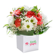 A delightful burst of floral colour and texture brightens this elegantly presented bouquet, reflecting the uplifting spirit of Wealdstone. Set within a sleek white gift bag, this arrangement gathers the gentle glow of coral and peach carnations with their decadent, ruffled petals, contrasting beautifully against the pure white of daisies whose eager green eyes sparkle with cheer. Baby's breath drifts delicately between the blooms, adding a cloud-like, ethereal softness reminiscent of early morning light in local parks. Peeking through on the left, unopened buds with a hint of purple suggest the subtle charm of spring waiting just around the corner-echoing the surprises one might find wandering Wealdstone's familiar avenues. Swaths of shiny, deep green foliage cradle the bouquet, shaping it into a rounded, abundant form that speaks of the careful attention Flowers Wealdstone brings to each arrangement. The immaculate white background and practical yet stylish bag together ensure that the vivid freshness of the flowers stands at the fore. Ideal for marking meaningful milestones, brightening up birthdays, or simply sharing a joyful moment, this bouquet promises a heartfelt, sensory experience delivered to doorsteps across Wealdstone.